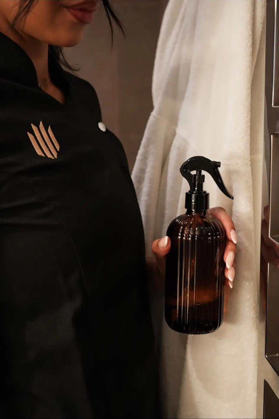 Vonula London cleaner in branded uniform holding an eco-friendly spray in a luxury bathroom